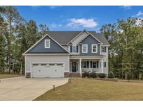Two-story home with gray and blue siding, a three-car garage, and a landscaped lawn at 63 Eastland Ct, Smithfield, NC 27577