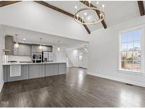 Open-concept living area featuring a modern kitchen, wood floors, and a vaulted ceiling with exposed beams and a chandelier at 520 S Bloodworth St, Raleigh, NC 27601