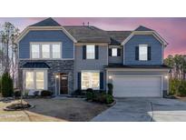 Two-story house with gray and blue siding, stone accents, and a two-car garage at 90 Cordova St, Clayton, NC 27527