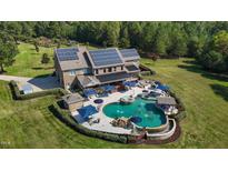 Aerial view of a luxury home featuring a large pool, outdoor seating, and solar panels at 415 Trotting Trl, Efland, NC 27243