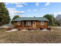 Charming log cabin with green roof, stone pathway, and landscaping at 1018 Lakeview Dr, Cedar Grove, NC 27231