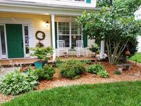Charming front porch with rocking chairs, vibrant landscaping, and a welcoming green door at 1201 Bethpage Dr, Mebane, NC 27302