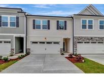 Charming townhome featuring a two-car garage, black shutters, and light beige siding at 7117 Hubner Pl # 22, Cary, NC 27519