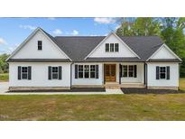 Charming white farmhouse with black shutters, a modern entrance and well-maintained landscaping at 250 Ellington Rd, Graham, NC 27253