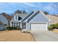 Charming home featuring a well-manicured lawn, blue siding, and an attached two-car garage at 701 Brickstone Dr, Apex, NC 27502