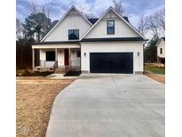 Charming two-story modern farmhouse with a black two car garage and a manicured front yard at 727 Cook Rd, Durham, NC 27713