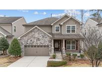Charming two-story home with stone accents, covered front porch, and attached two-car garage at 1259 Magnolia Row Trl, Apex, NC 27502
