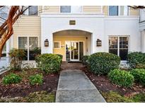 Condo entrance with a brick archway, glass door, address, and mature landscaping framing the walkway at 1300 Durlain Dr # 108, Raleigh, NC 27614