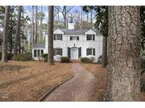 Charming two-story home with white painted brick, black shutters, and a brick walkway at 2706 Rosedale Ave, Raleigh, NC 27607