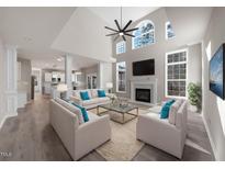 Bright living room features a fireplace, large windows, ceiling fan, and stylish furniture at 4703 Paces Ferry Dr, Durham, NC 27712