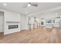 Bright living room featuring an electric fireplace, hardwood floors and a smooth transition to the kitchen at 4804 Cypress Tree Ln, Raleigh, NC 27612