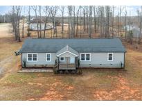 Single-story home with gray siding, a covered porch, and a large yard at 5724 Walters Ln, Burlington, NC 27217