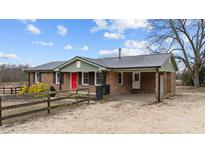 Charming brick home featuring a metal roof, red front door, and covered parking area at 593 Bailey Rd, Coats, NC 27521