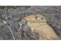 Expansive aerial view of a multi-building farm estate with fenced pastureland and surrounding woods at 7700 Circle L Trl, Rougemont, NC 27572