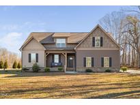 Two-story home with brown siding, a covered porch, and a grassy lawn at 182 River Ridge Ln, Timberlake, NC 27583