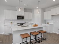 Bright kitchen featuring white cabinets, stainless steel appliances and a large island with stool seating at 3860 Well Fleet Drive, Fuquay Varina, NC 27526