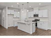 Modern kitchen with island, stainless steel appliances, and white cabinets at 3860 Well Fleet Drive, Fuquay Varina, NC 27526