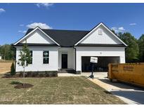 Charming single-story home with white siding, black door, and attached garage, set against a blue sky at 45 Mossman Ct, Zebulon, NC 27597