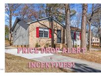 Charming brick and siding home featuring bright red shutters and manicured landscaping at 2400 Keith Dr, Raleigh, NC 27610