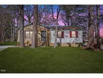 Brick ranch house with red shutters, a spacious lawn, and a tree-lined setting at 2400 Keith Dr, Raleigh, NC 27610