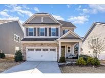 Two-story home with gray siding, stone accents, and a two-car garage at 328 Golf Vista Trl, Holly Springs, NC 27540