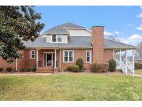 Brick home with a large covered porch and landscaped lawn at 3406 Sir Colleton Ct, Raleigh, NC 27612