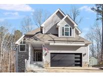 Two-story home with gray siding, stone accents, and a modern garage door at 5920 Orchid Valley Rd, Raleigh, NC 27613