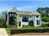 Stunning white brick home featuring black trim, gorgeous landscaping, and a meticulously maintained lawn at 1324 Brooks Ave, Raleigh, NC 27607