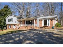 Brick ranch house with a large driveway and mature trees at 326 W Bywood Dr, Durham, NC 27712