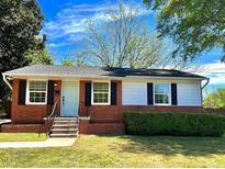 Charming one-story brick home with a manicured lawn and lush green bushes. A welcoming entrance makes this home appealing at 1206 Downing Rd, Raleigh, NC 27610