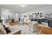 Open concept living room featuring hardwood floors, modern lighting, and an eat-in kitchen at 5232 Guess Rd, Durham, NC 27712