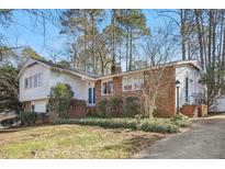 Charming brick home with manicured front lawn, mature trees, and blue front door at 5410 Thayer Dr, Raleigh, NC 27612