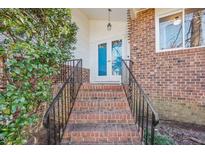 Charming brick home entrance with blue double doors, black railings, and lovely landscaping at 5410 Thayer Dr, Raleigh, NC 27612