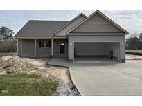 Charming single-story home with a large driveway and attached two-car garage at 68 Tee Dr, Selma, NC 27576