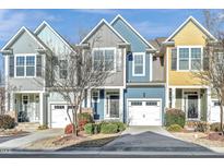 Charming colorful townhomes featuring attached garages and well-maintained landscaping at 103 Hundred Oaks Ln, Holly Springs, NC 27540