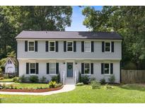 Charming two-story home with a blue door and a well-manicured front lawn at 106 N Trail Dr, Raleigh, NC 27615