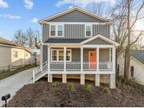 Charming two-story home featuring a covered front porch with a bright orange front door at 107 Bond St, Durham, NC 27707