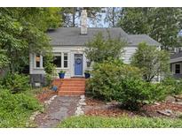Charming home with a brick walkway, blue door, and well-manicured landscaping at 1813 University Dr, Durham, NC 27707