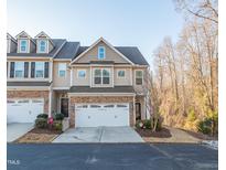 Charming two-story townhome featuring a two-car garage and a stone-accented facade at 256 Wembley Dr, Clayton, NC 27527