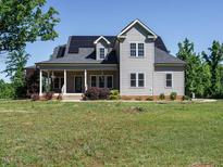 Charming two-story home featuring solar panels, a welcoming front porch and manicured landscaping at 3958 Buckhorn Rd, Sanford, NC 27330
