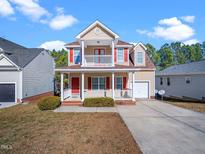 Charming two-story home featuring a front porch, second-story balcony, and well-maintained landscaping at 5841 Wynmore Rd, Raleigh, NC 27610