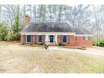 Charming brick home with dark shutters, a chimney, and a well-maintained front yard at 612 W Chisholm St, Sanford, NC 27330