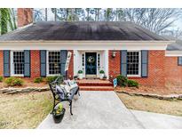 Charming brick home featuring blue shutters, manicured landscaping, and a welcoming entryway at 612 W Chisholm St, Sanford, NC 27330