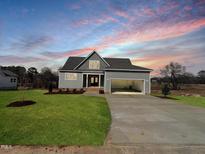 Charming home featuring well-manicured lawn, attached two car garage, and inviting entry way at 83 Nottoway Lane, Wendell, NC 27591