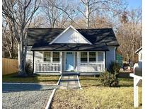 Charming home with a covered porch, blue front door, and landscaped front yard at 1210 Shaw St, Burlington, NC 27217