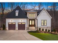 Elegant two-story home featuring a stone and white facade, complemented by a well-manicured lawn and mature trees at 227 Beech Slope Ct, Chapel Hill, NC 27517