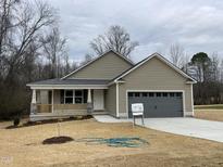 Charming single-story home featuring neutral siding, a welcoming front porch, and an attached two-car garage at 416 Magnolia Run Way, Benson, NC 27504