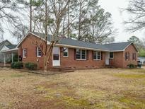 Charming brick home featuring red shutters, a well-manicured lawn, and mature trees at 431 Mattox St, Wendell, NC 27591