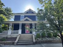 Charming two-story home featuring a vibrant pink front door, inviting porch, and well-maintained landscaping at 101 S Bloodworth St, Raleigh, NC 27601