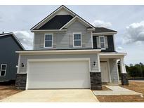 New two-story home featuring gray siding, a two-car garage, and a covered front porch at 135 Willow Cameron Way, Angier, NC 27501